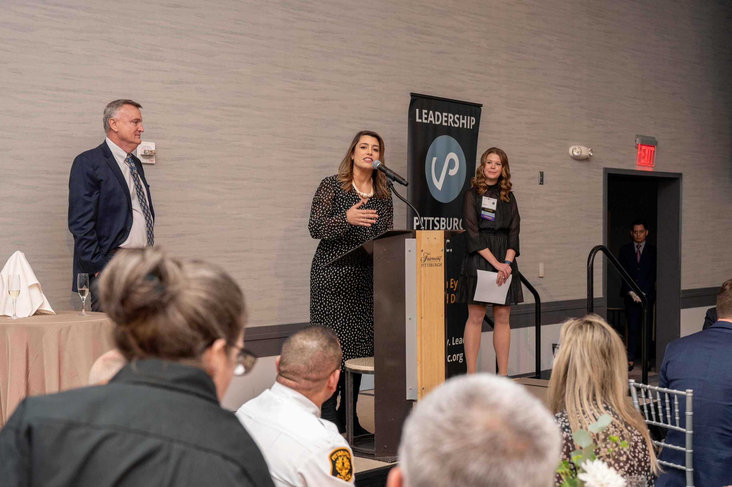 John Olin, CFO of Wabtec, Event Presenting Sponsor and Jenn Beer LDI XVII, YALP IV – Leadership Pittsburgh Inc. President and CEO on stage while Allegheny County Executive Sara Innamorato provides remarks.